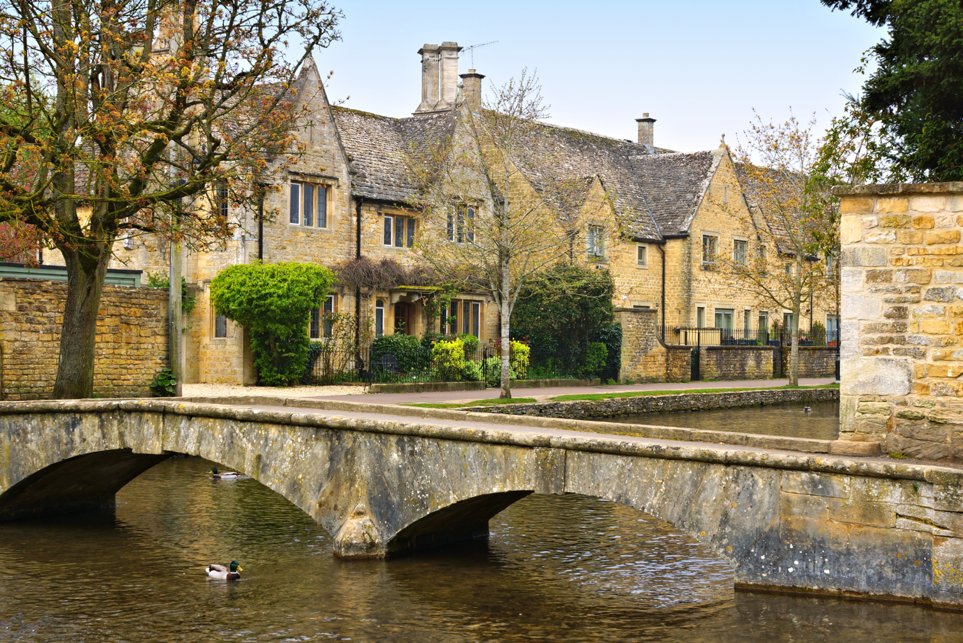 Stone bridge crossing River Windrush with traditional Cotswold cottages in Bourton-on-the-Water.
