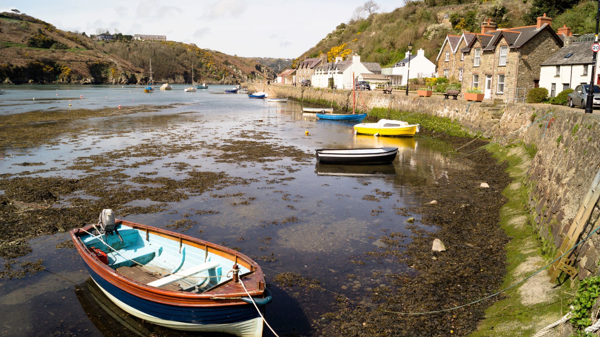 Small boats moored in a quiet Pembrokeshire harbour village on a self-guided walking route.
