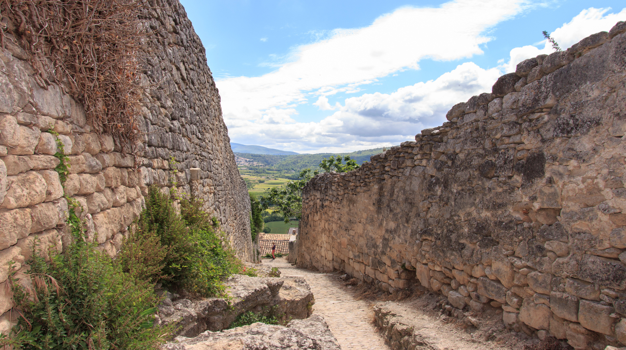 Stone path between old village walls in Lacoste with views across the Luberon