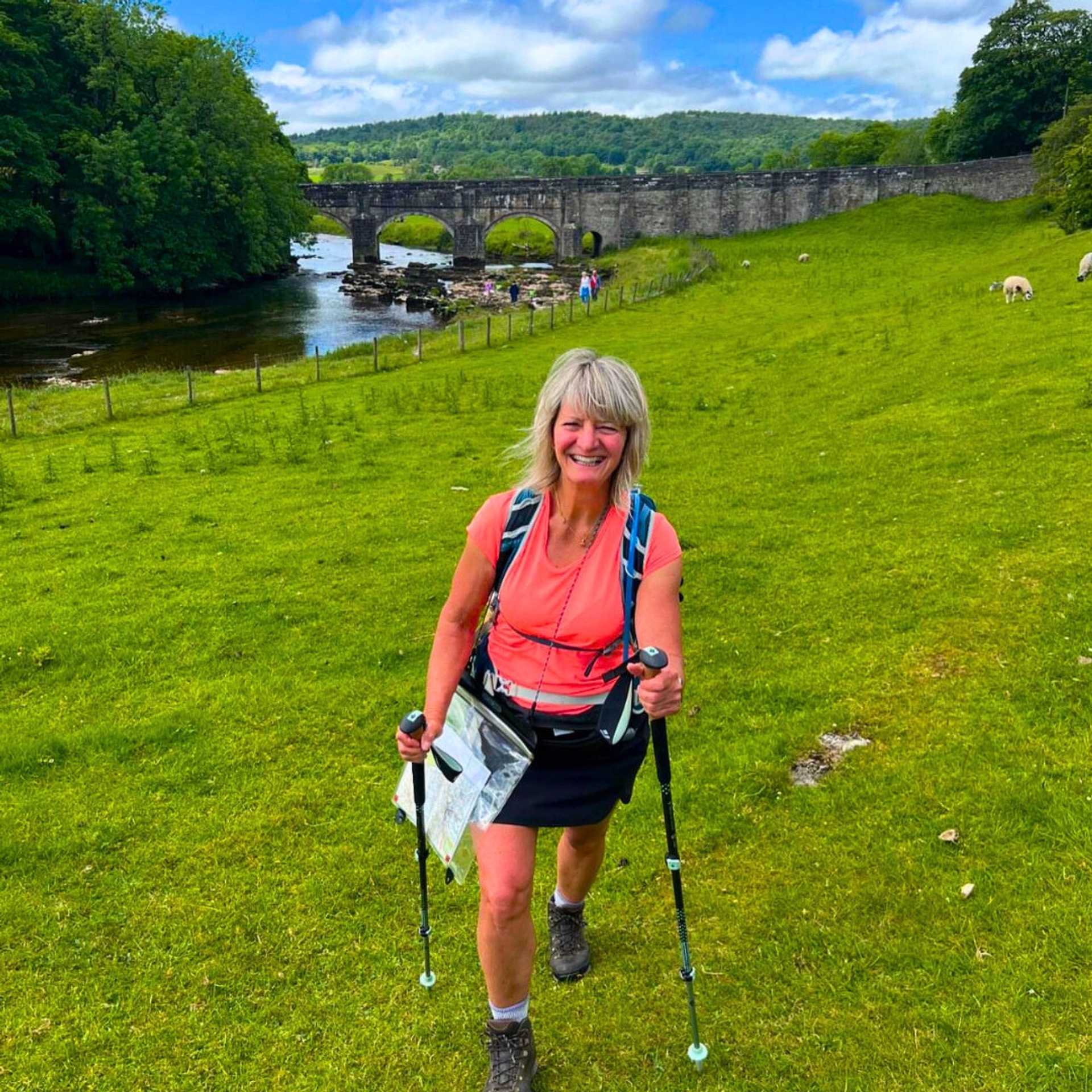 Walker approaching a historic stone bridge on the Dales Way in the Yorkshire Dales