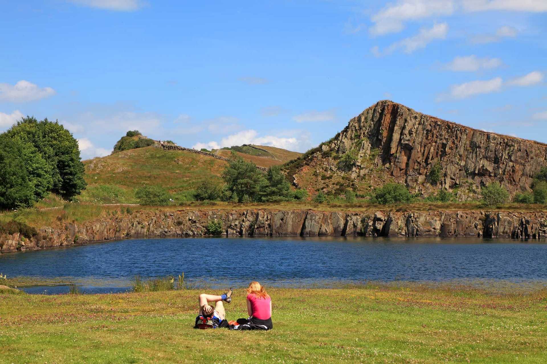 Walkers resting by Cawfields Quarry with Cawfields Crag on Hadrian’s Wall Path