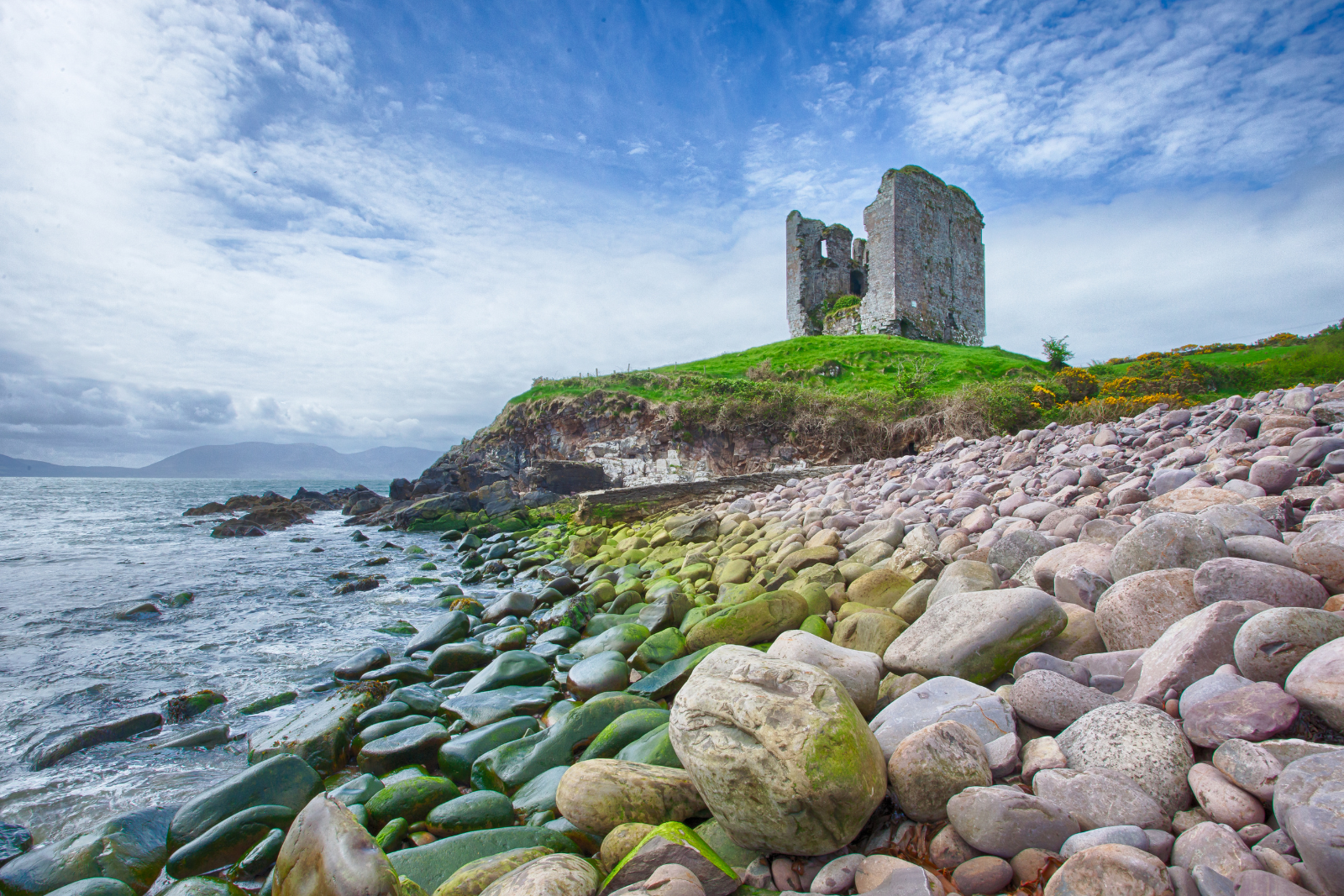 Ruins of Minard Castle overlooking a rocky beach on the Dingle Peninsula.