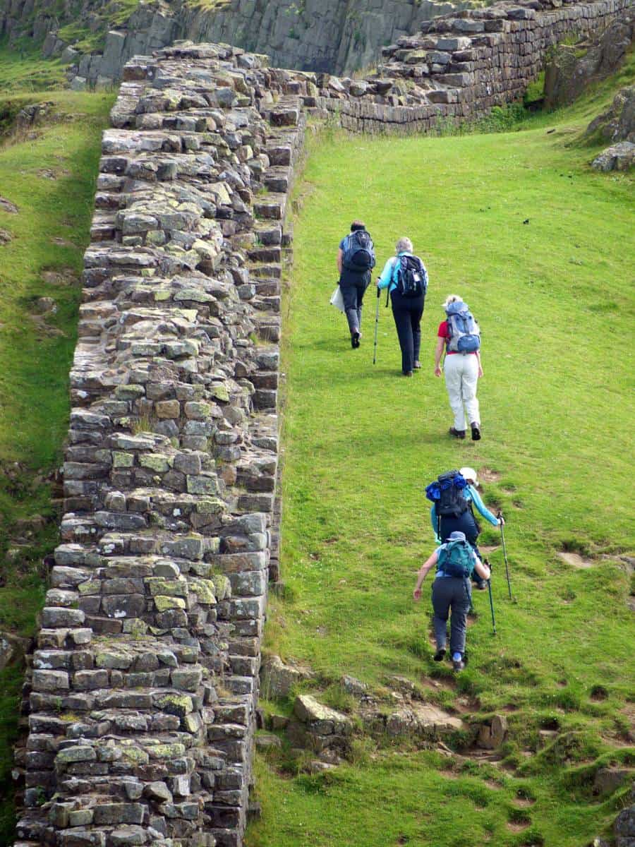 Walkers ascending beside Hadrian’s Wall on the Whin Sill escarpment in Northumberland