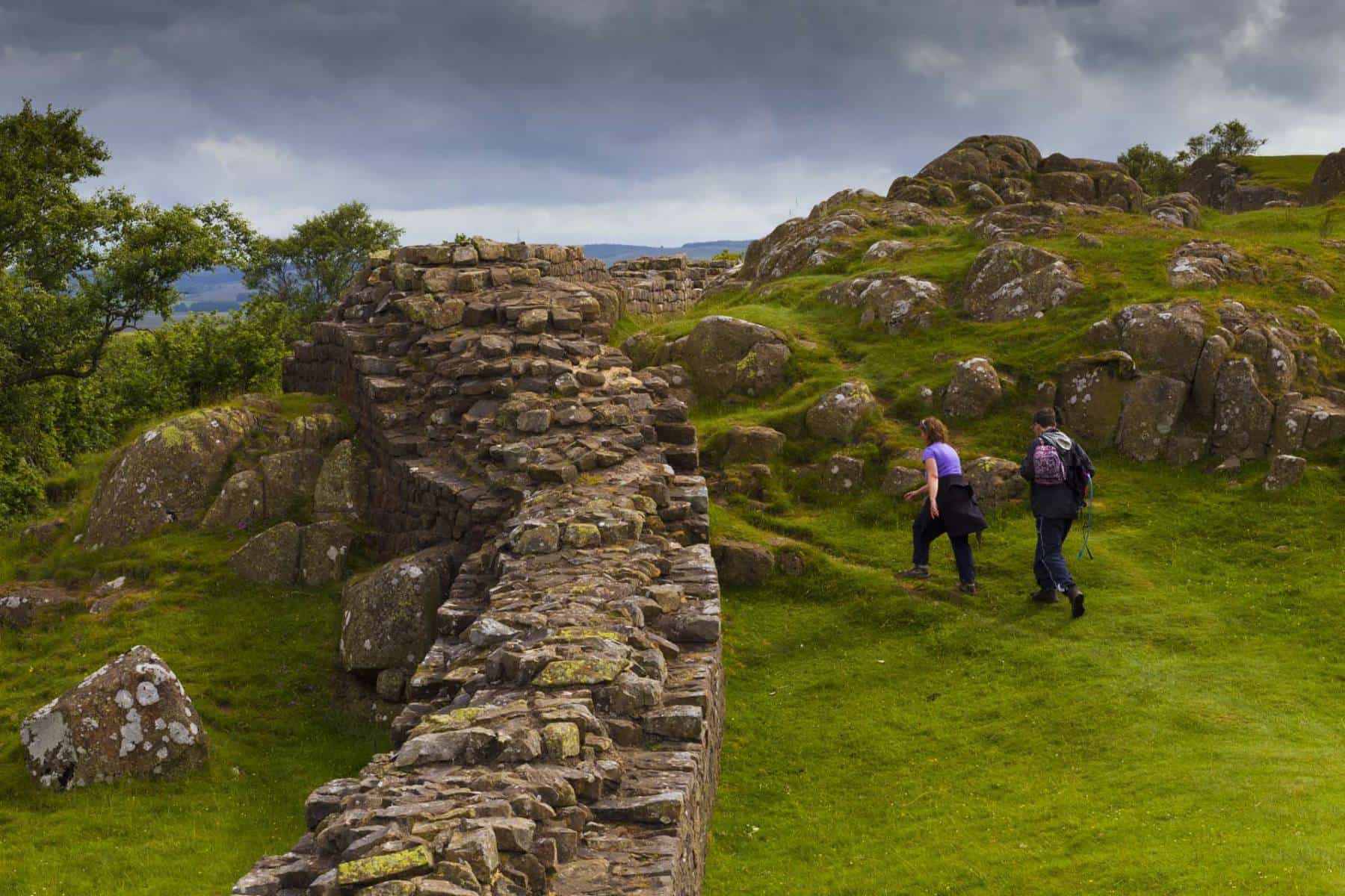 Walkers beside Hadrian’s Wall on rocky moorland in Northumberland National Park