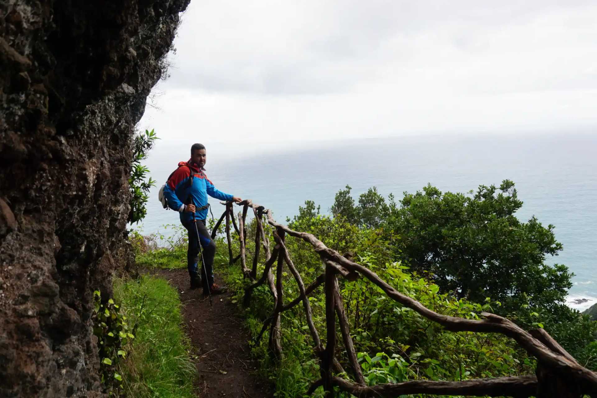 Walker on a coastal path overlooking the Atlantic Ocean on Madeira's rugged north coast.