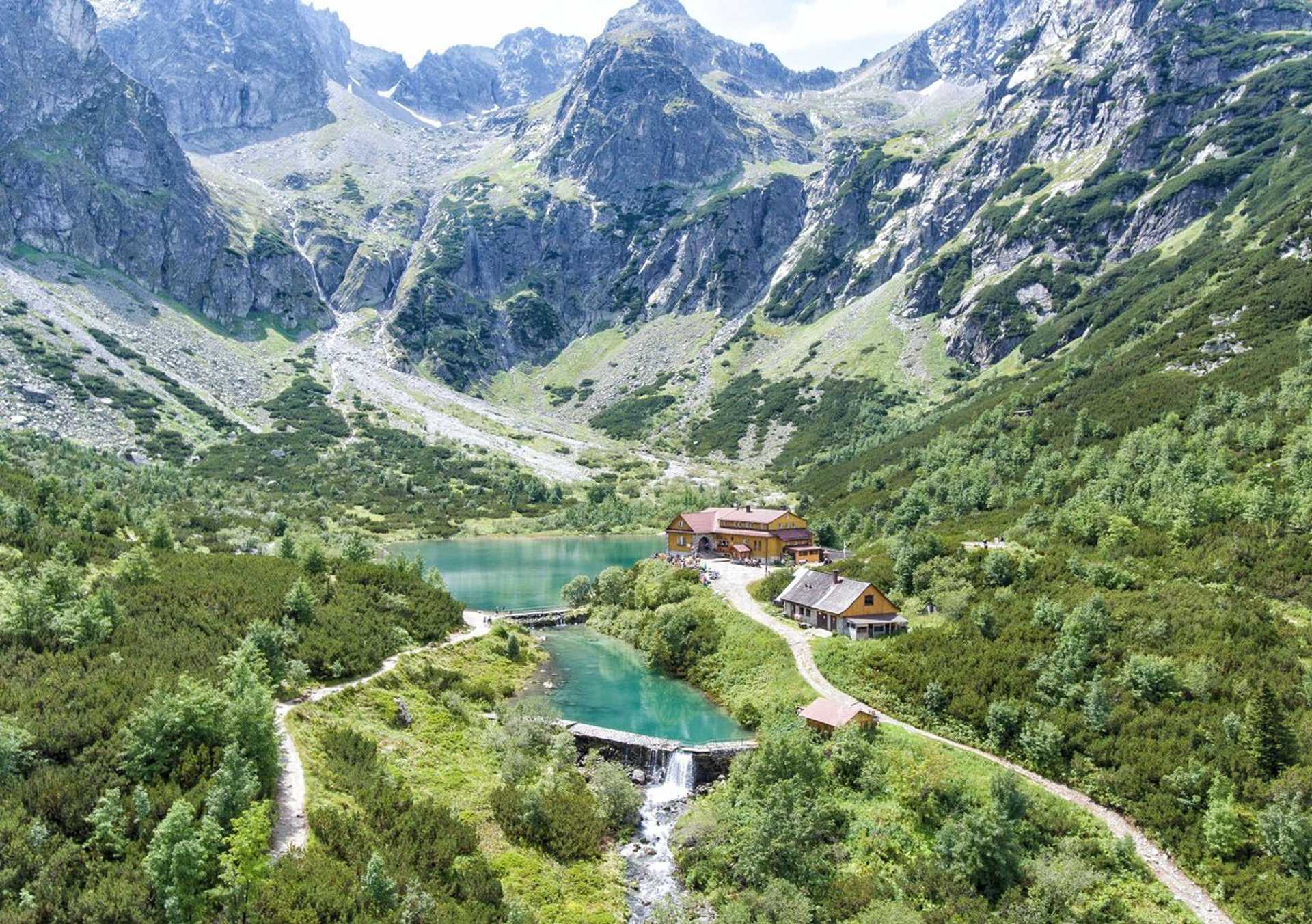 Walking path beside Zelené Pleso glacial lake with mountain hut and peaks in the High Tatras