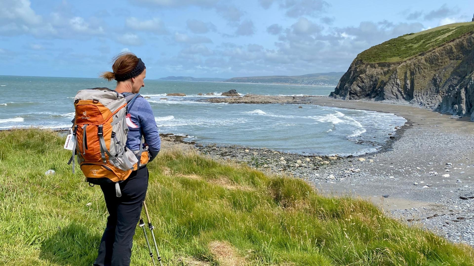 Walker on the Ceredigion Coast Path above a rocky bay