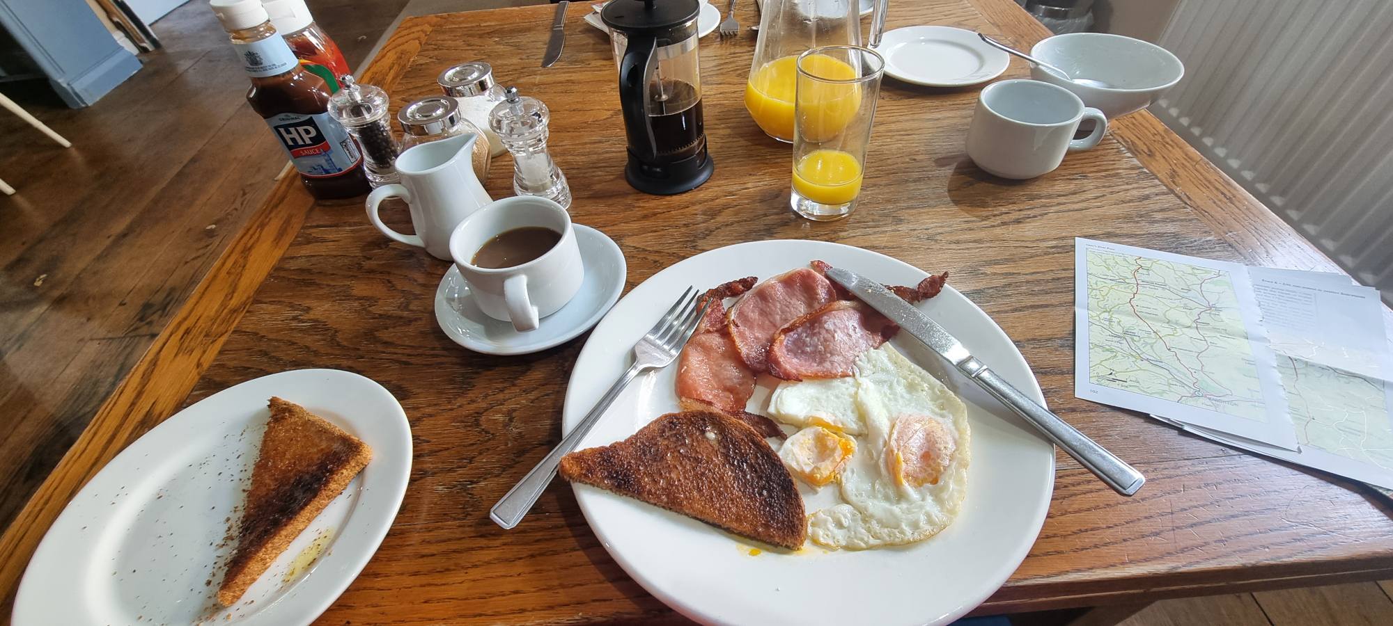 Coffee, toast, bacon and egg and map laid out before a self-guided walking day.