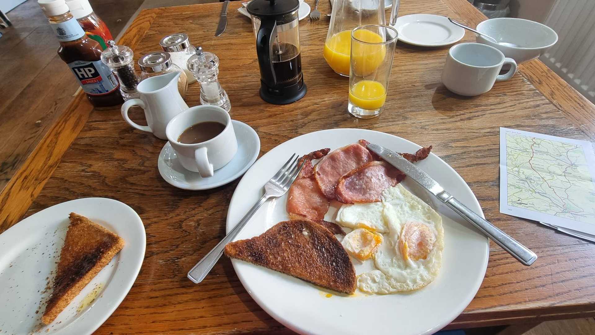 Coffee, toast, bacon and egg and map laid out before a self-guided walking day.