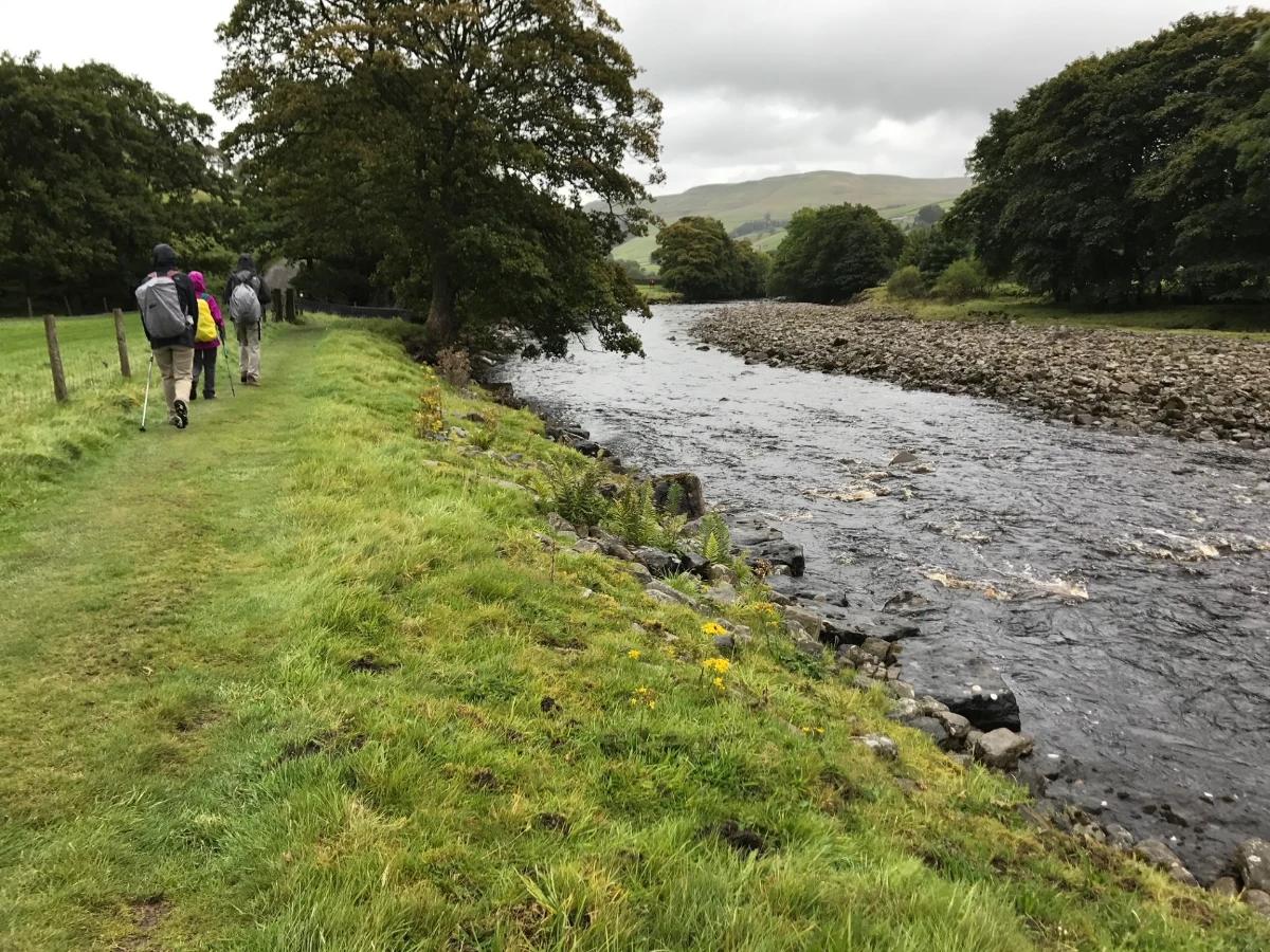Walkers following a riverside path near Keld on the Coast to Coast Walk