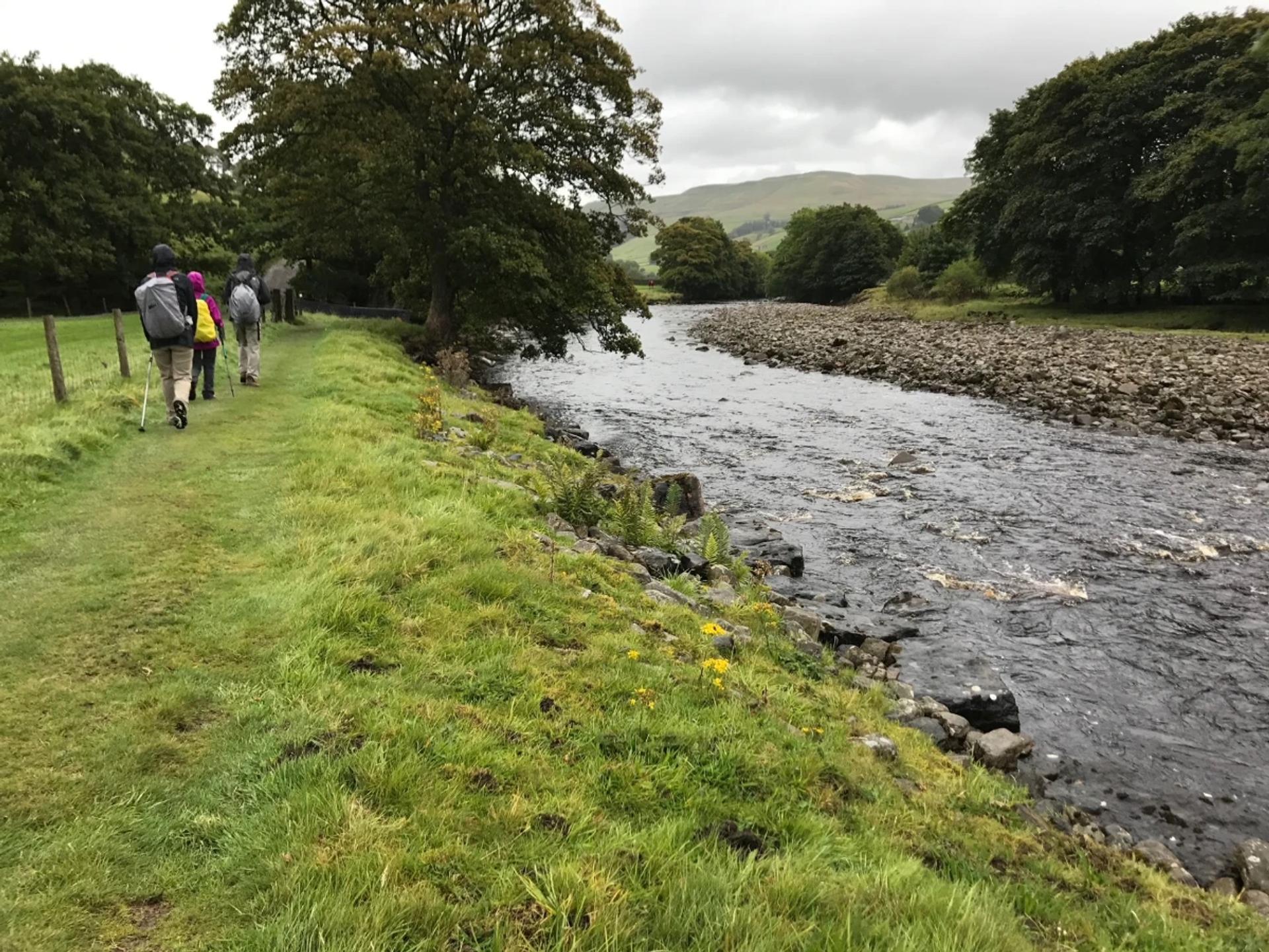 Walkers following a riverside path near Keld on the Coast to Coast Walk