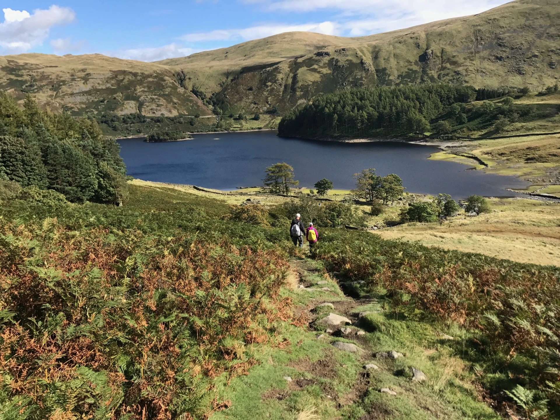 Walkers descending towards a mountain lake in the Lake District on the Coast to Coast Walk