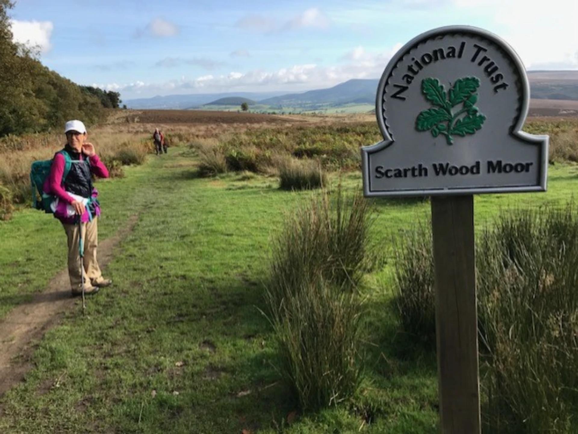 Walker passing the Scarth Wood Moor sign on the Coast to Coast Walk