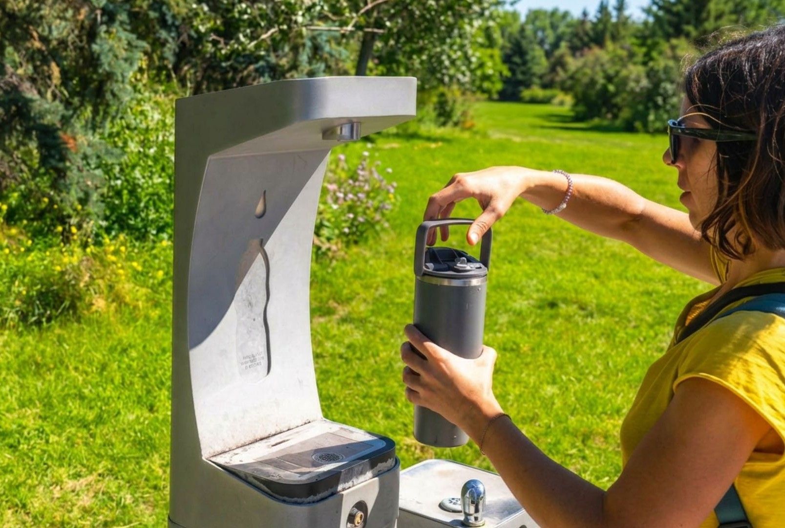 Walker refilling a reusable water bottle during a summer walking holiday