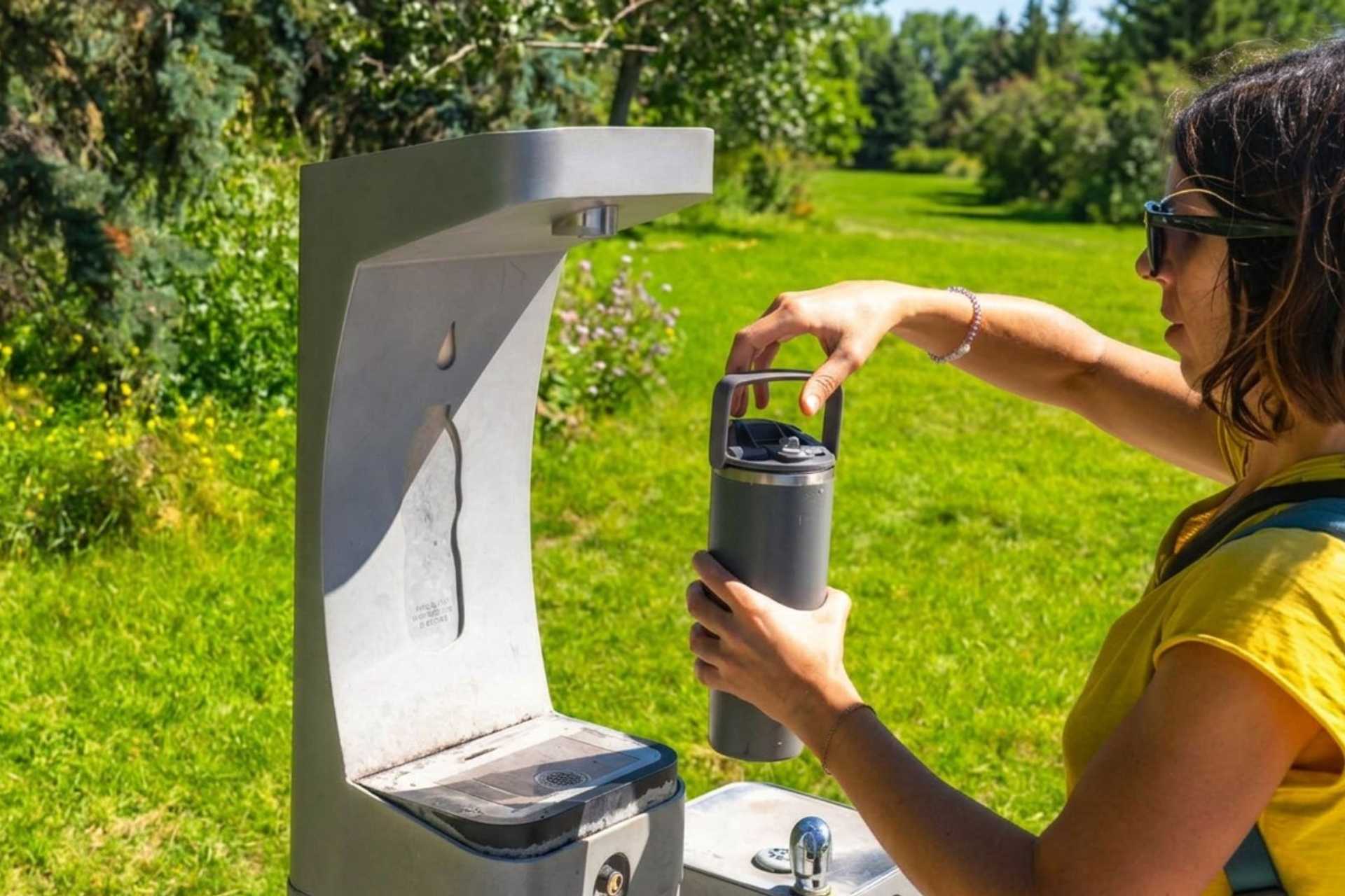Walker refilling a reusable water bottle during a summer walking holiday
