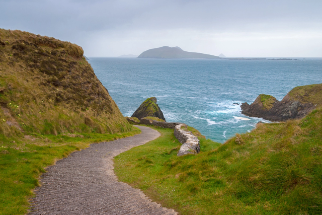 Coastal path descending towards Dunquin Pier, with an island visible offshore.