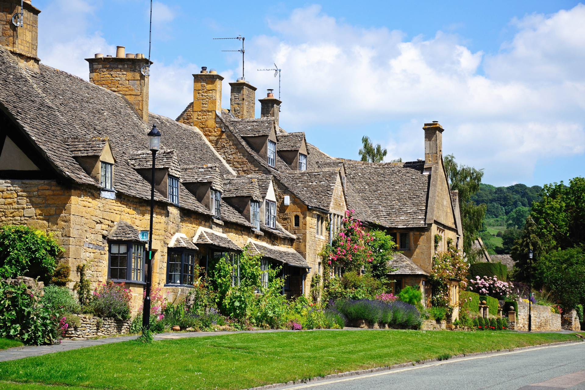 Traditional honey-coloured Cotswold stone cottages along a street in Broadway.