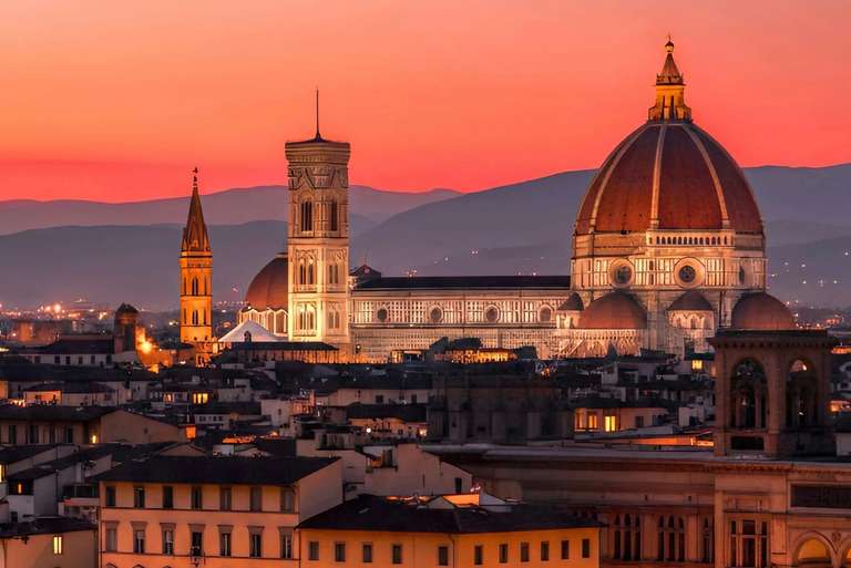 The Florence Cathedral and Giotto's Campanile are illuminated against a vibrant sunset sky, with rolling hills in the background.