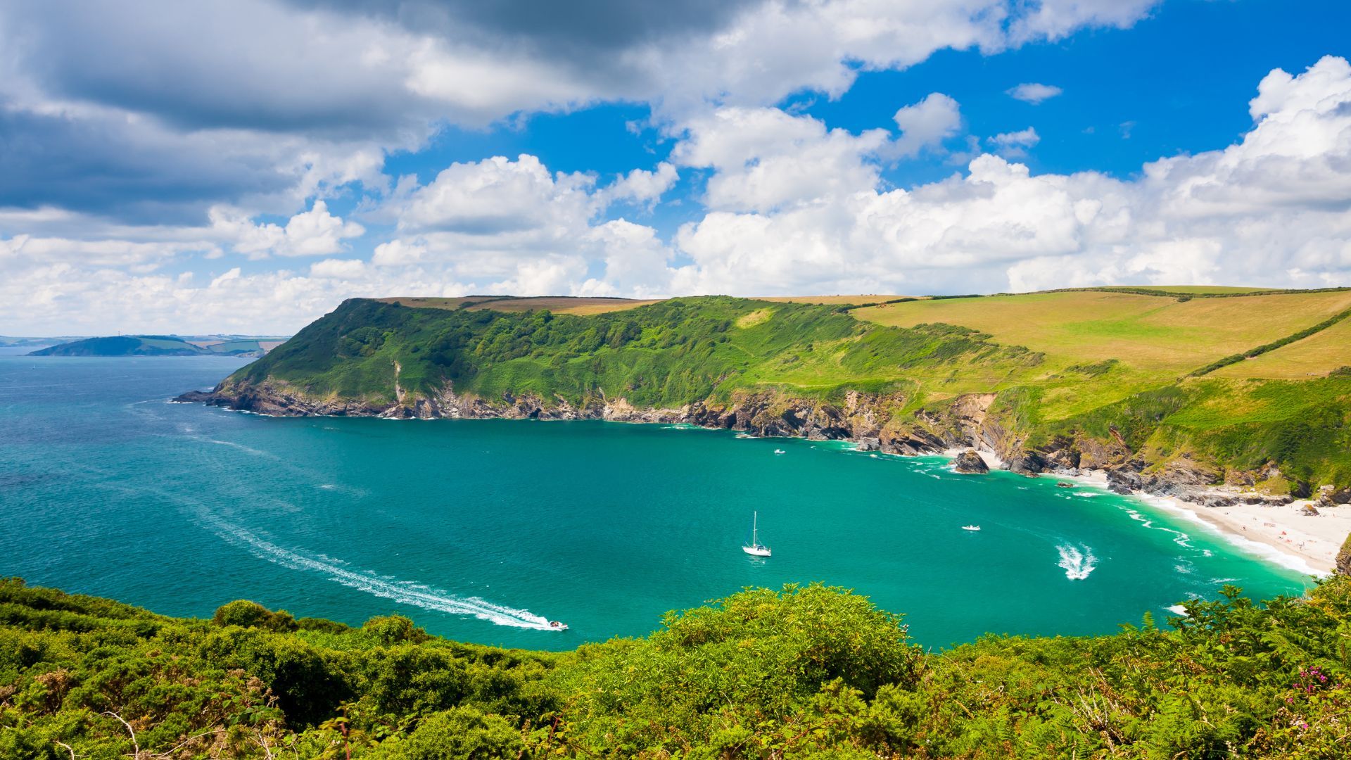 Barafundle Bay on the Pembrokeshire coast, with green cliffs and boats on the water.