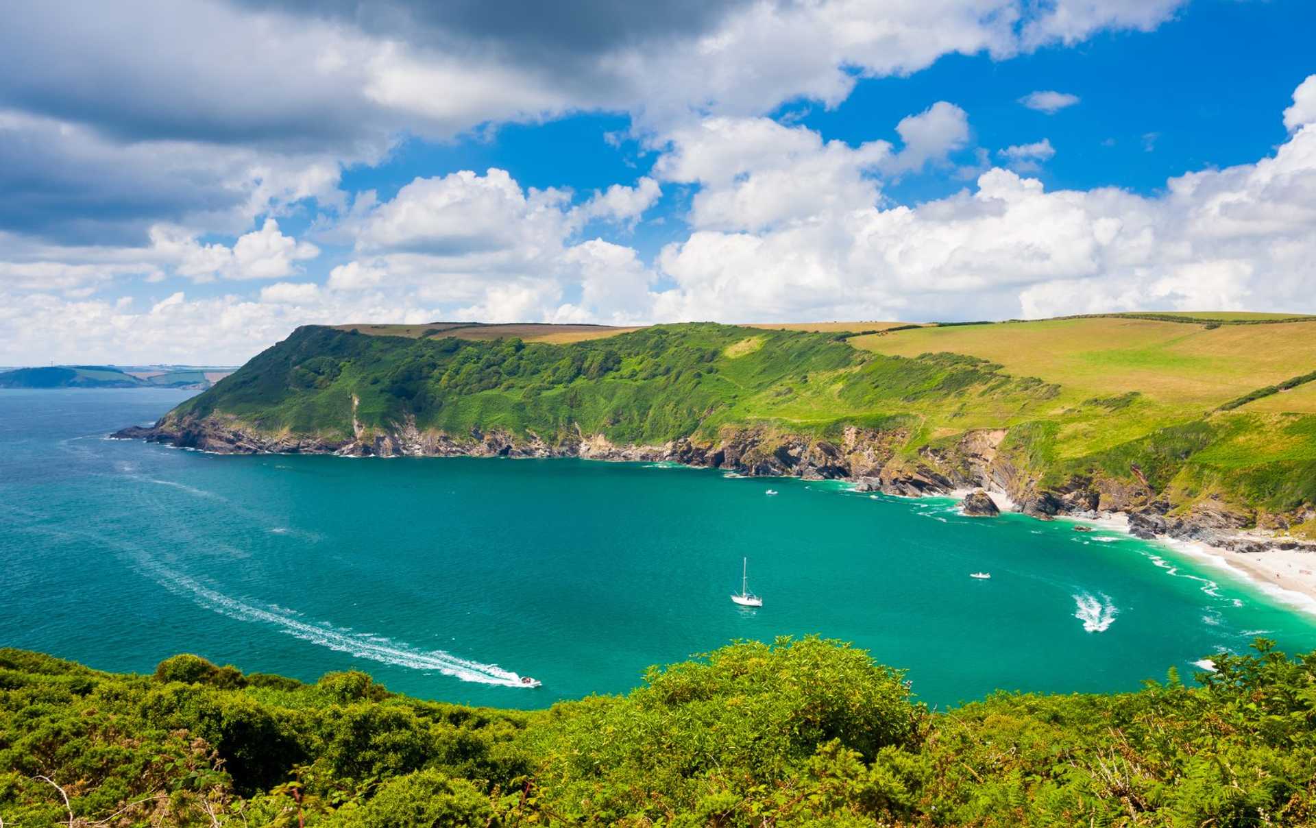Barafundle Bay on the Pembrokeshire coast, with green cliffs and boats on the water.