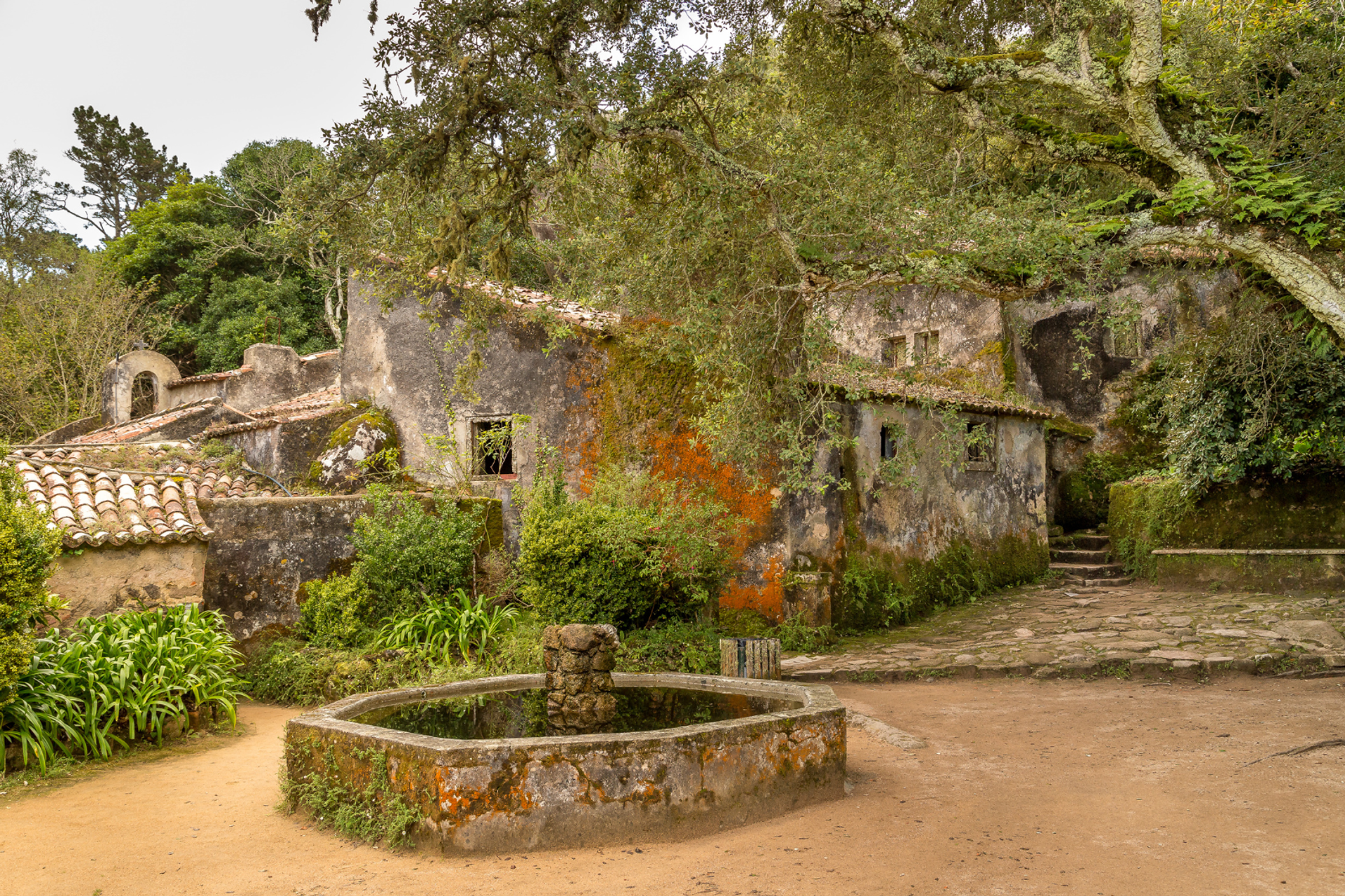 Weathered stone buildings of Convento dos Capuchos surrounded by woodland in Sintra.