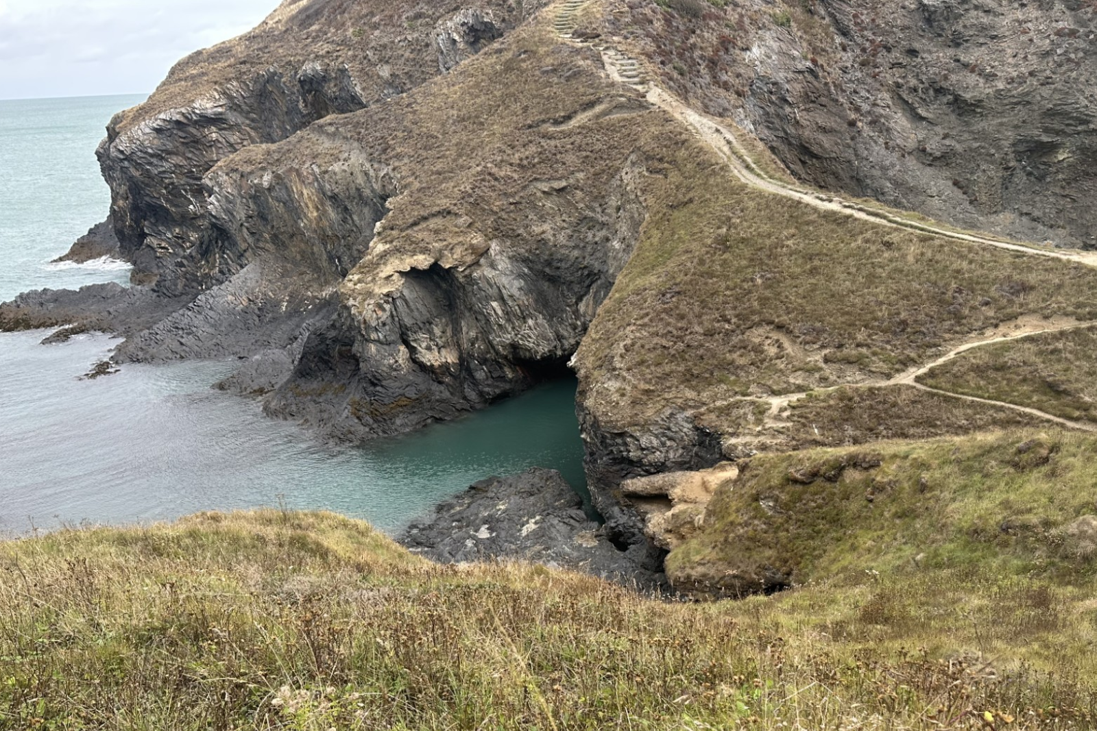 Coastal path descending around a rocky cove in Ceredigion
