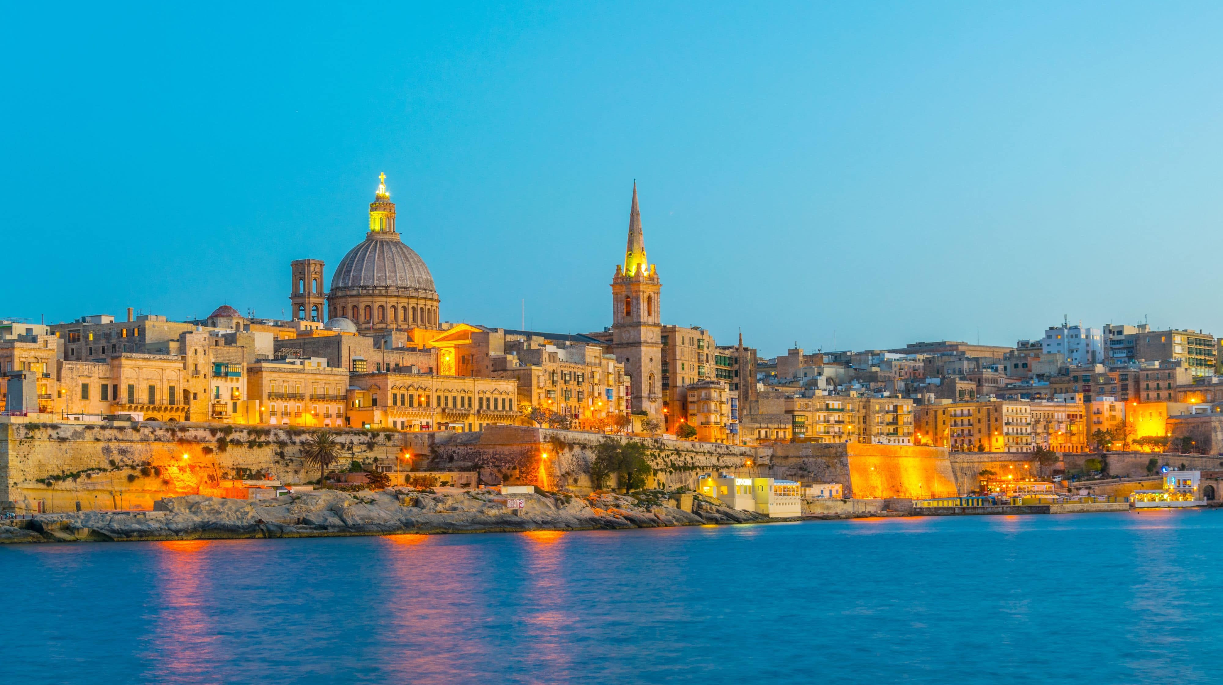 Valletta’s illuminated skyline at dusk overlooking the harbour.