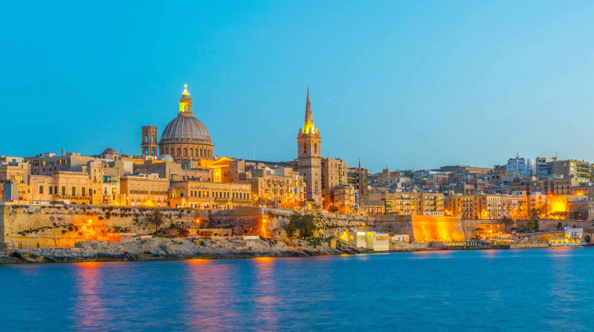 Valletta’s illuminated skyline at dusk overlooking the harbour.