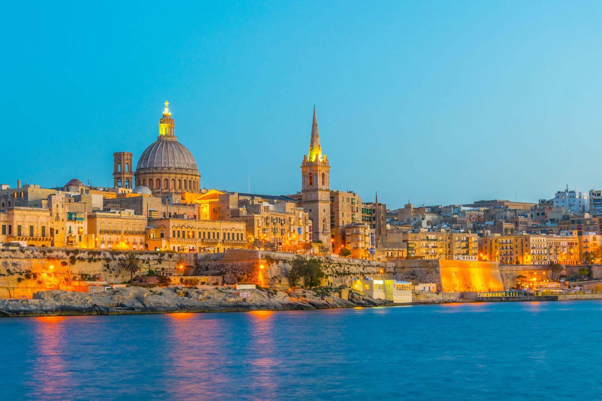 Valletta’s illuminated skyline at dusk overlooking the harbour.