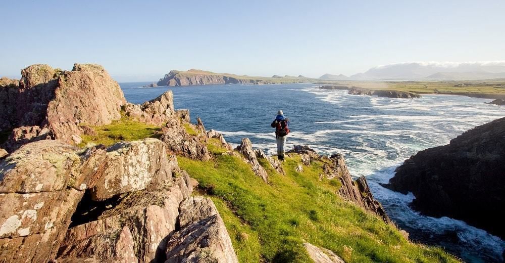 Walker on a rocky coastal section of the Dingle Way in Ireland overlooking the Atlantic coast