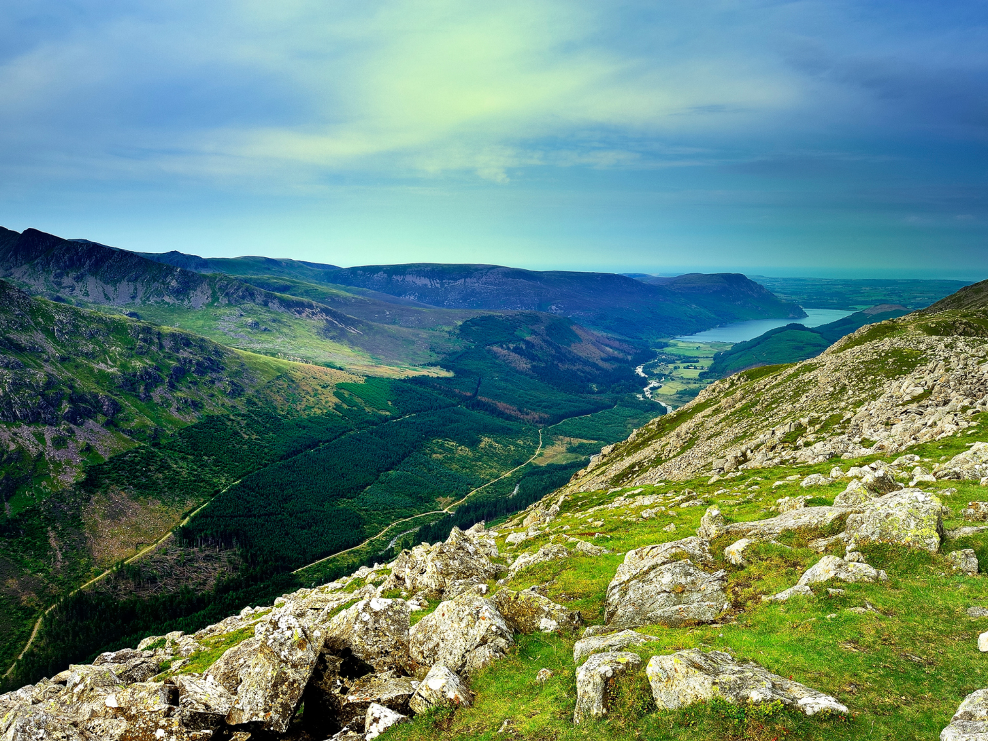 Rocky Lake District fells above a wooded valley on Wainwright’s Coast to Coast.