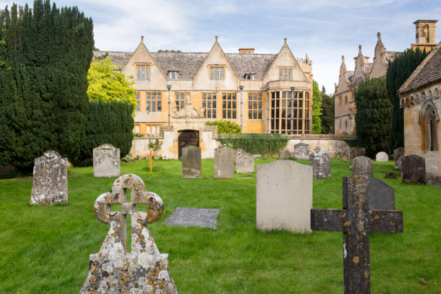 Historic stone building at Stanway, viewed across a churchyard.