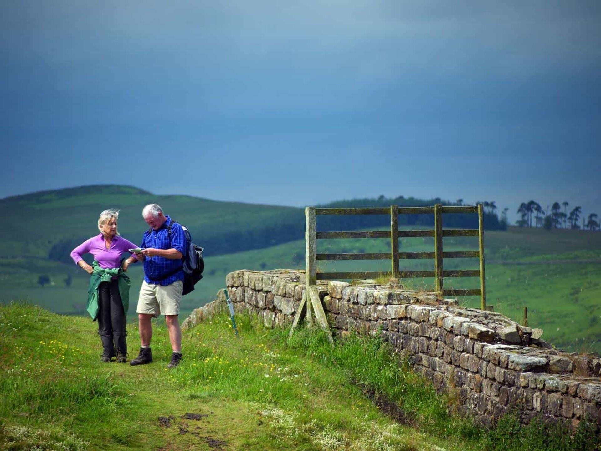 Walkers checking a map beside Hadrian’s Wall in Northumberland countryside