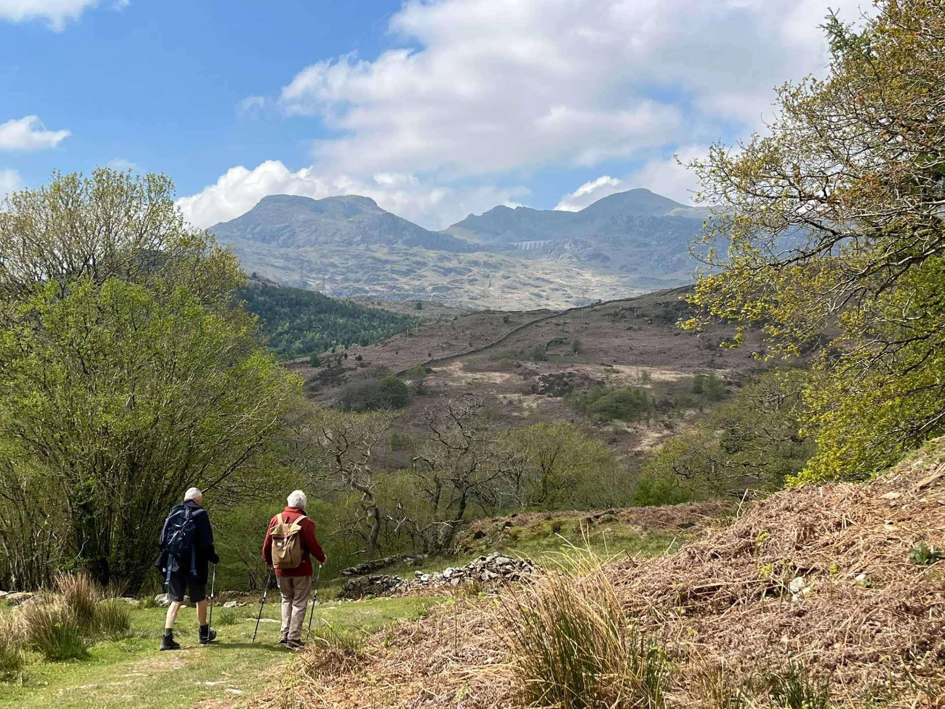 Two walkers with poles with mountain views