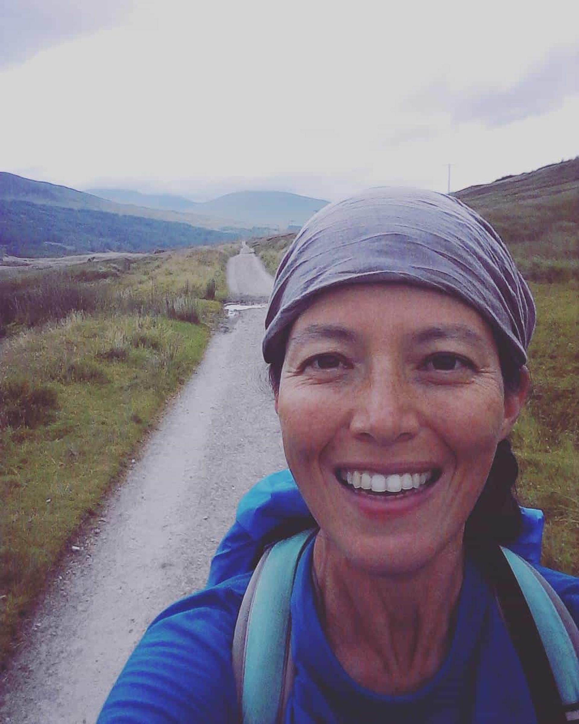 Smiling walker on the West Highland Way with hills in the background