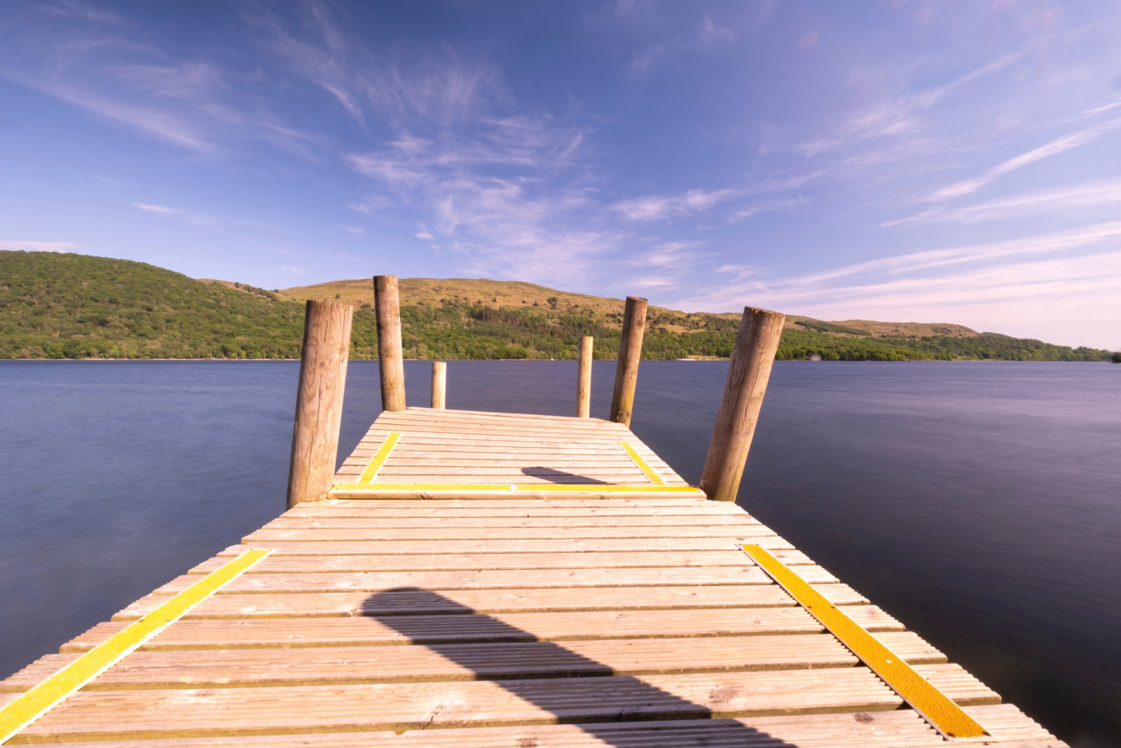 Wooden jetty on Coniston Water with the Lake District fells beyond.