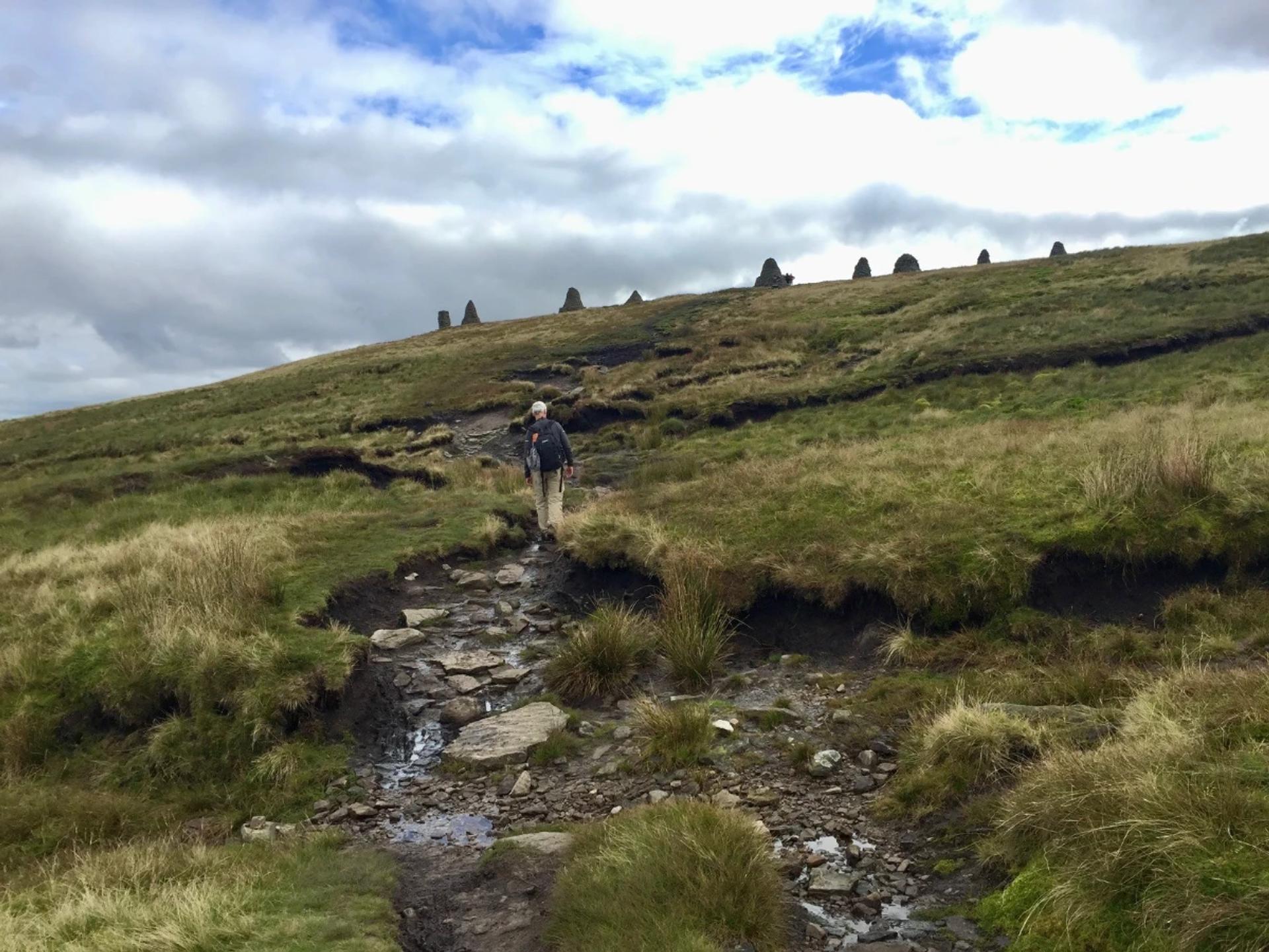 Walker approaching the Nine Standards Rigg cairns on the Coast to Coast Walk