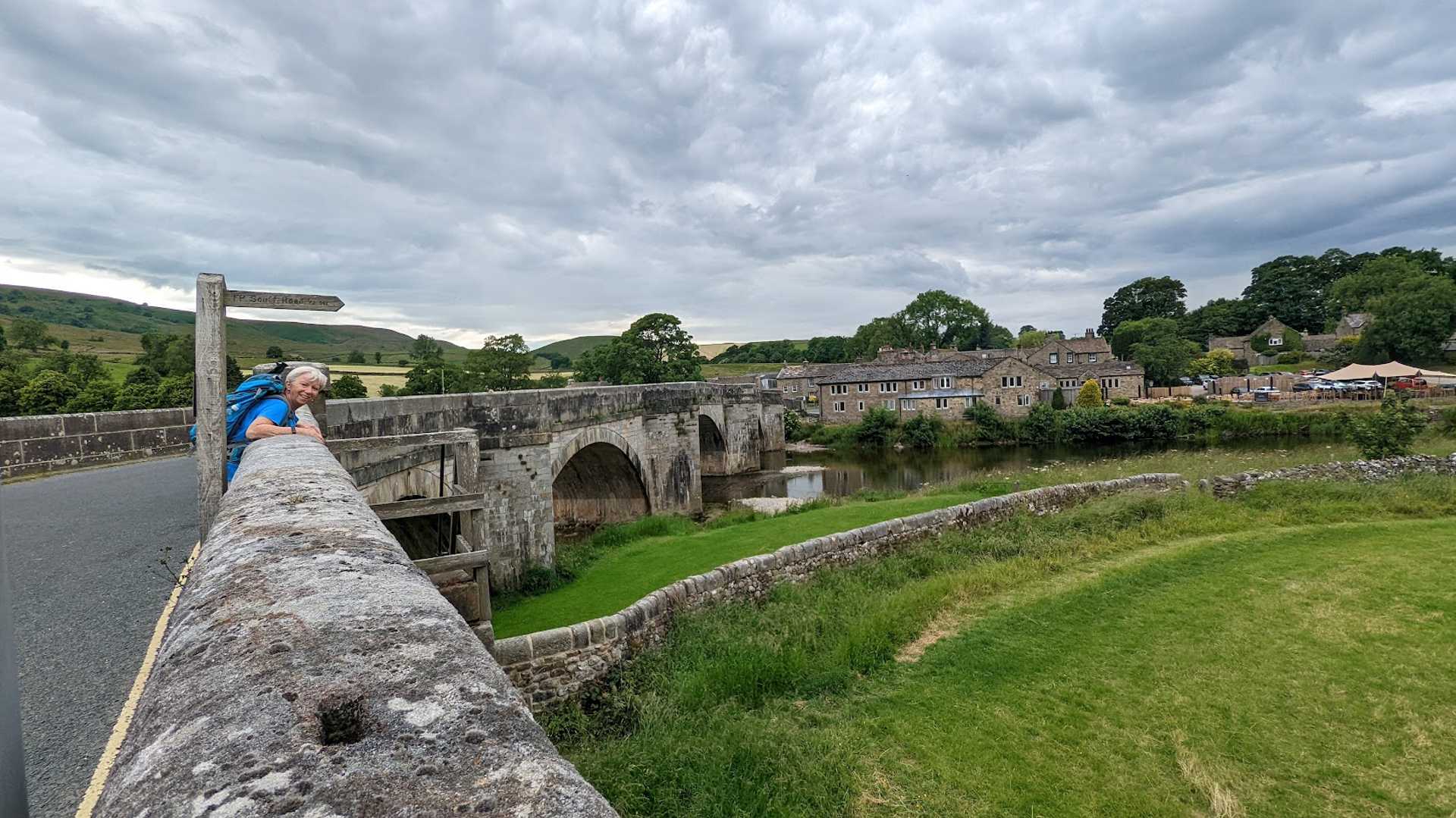 Walker crossing a historic stone bridge in the Yorkshire Dales on the Dales Way