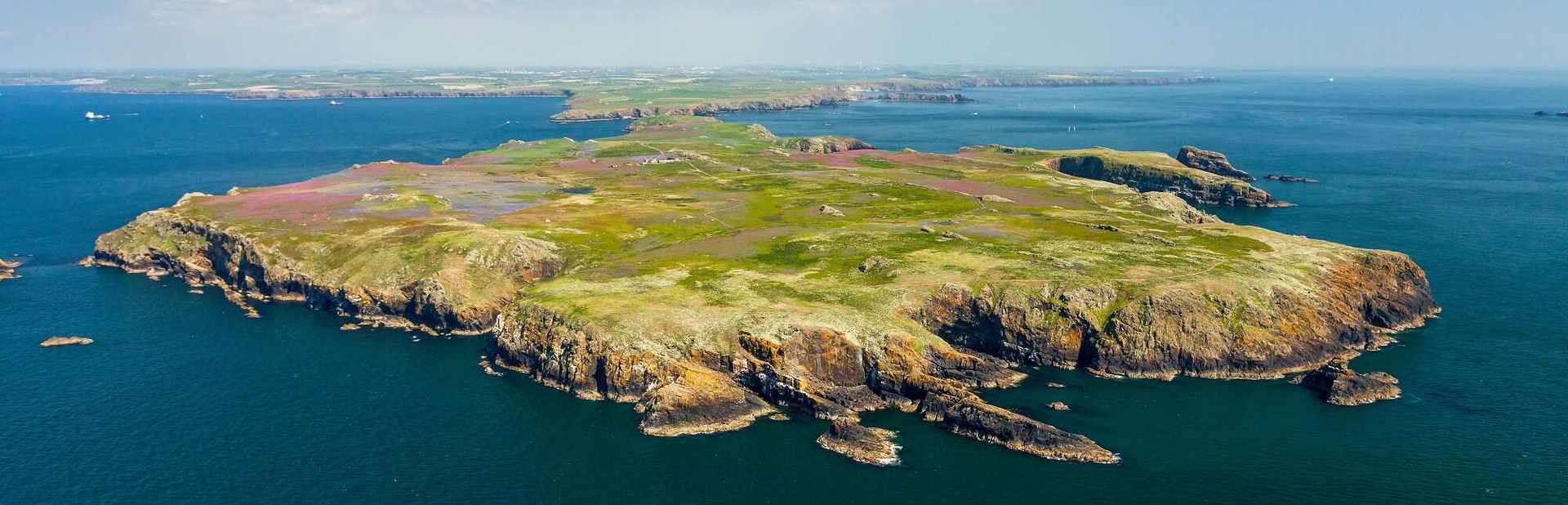 View from a plane of a small island surrounded by sea on a sunny day.