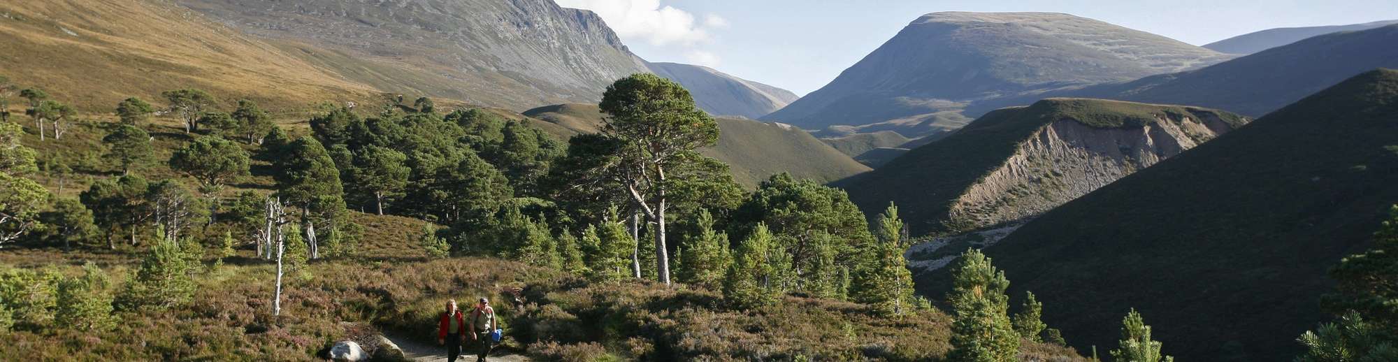 A couple of walkers on a track from the Lairig Ghru mountain pass (visible beyond) in the Cairngorms National Park, Highlands of Scotland