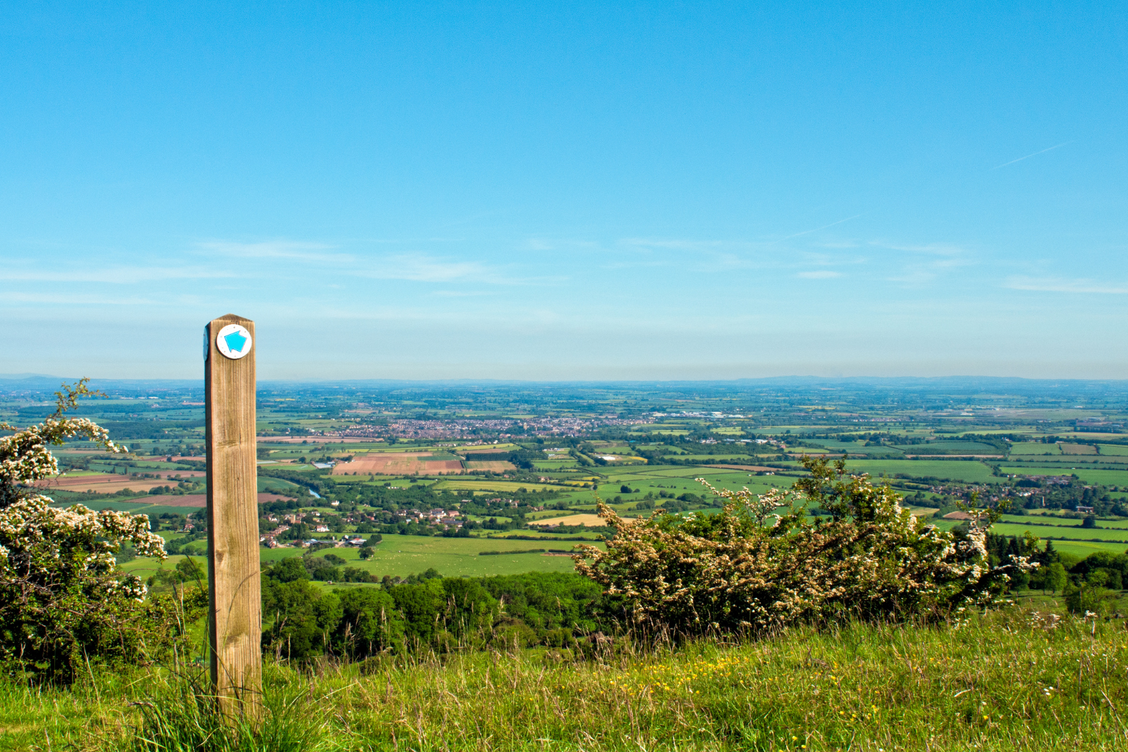 Cotswold Way waymarker overlooking rolling farmland.