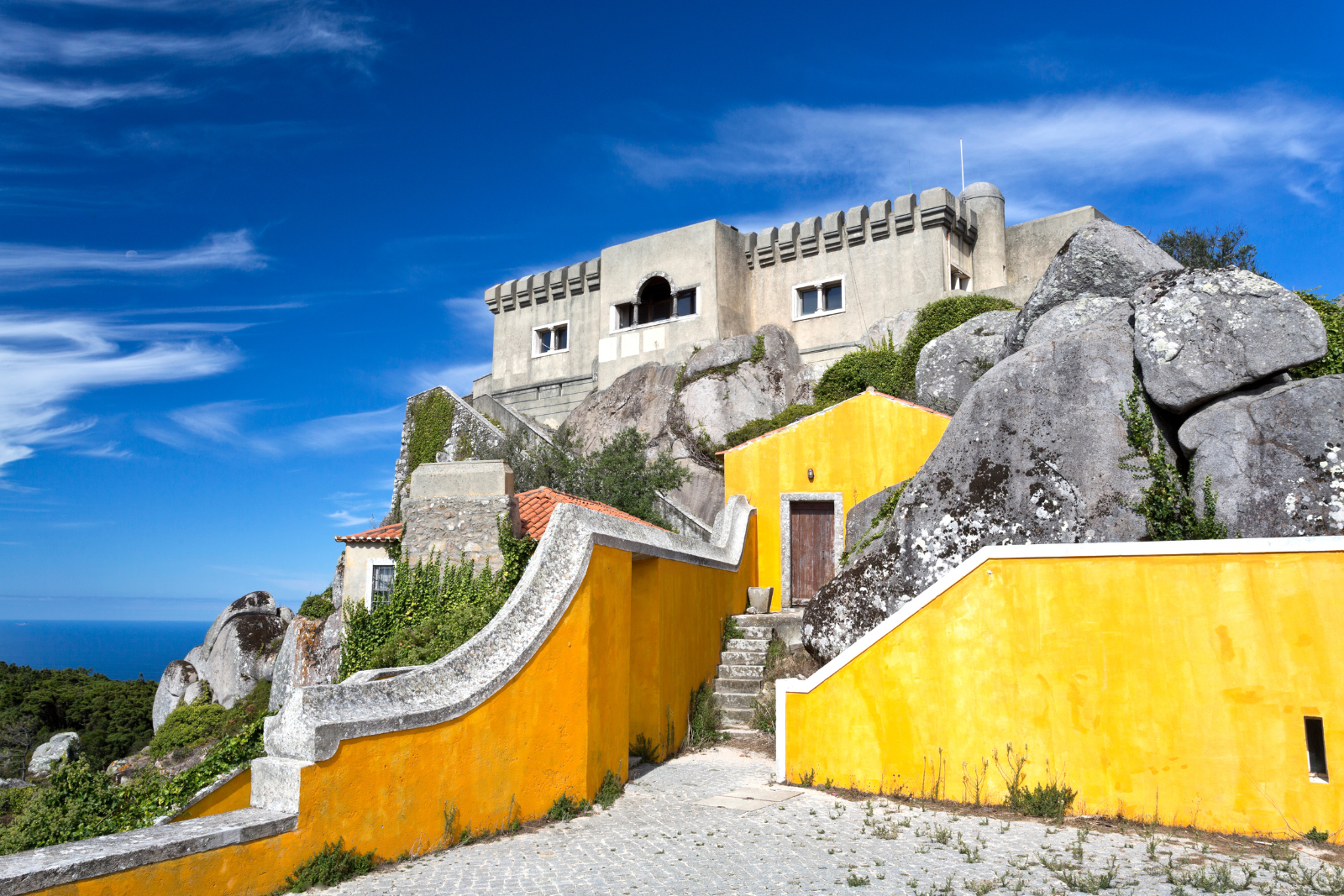 Yellow sanctuary walls and stone buildings among granite rocks at Peninha, Sintra.