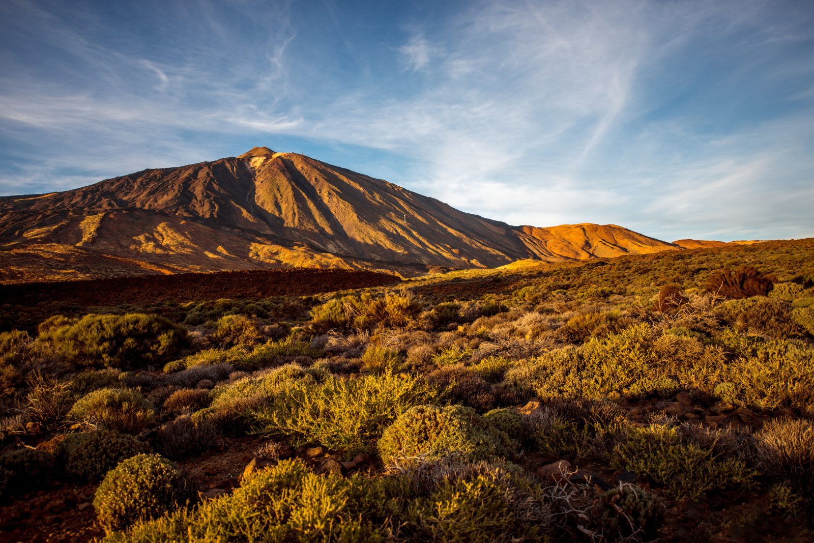 Mount Teide in evening sunlight above volcanic hills in Tenerife.