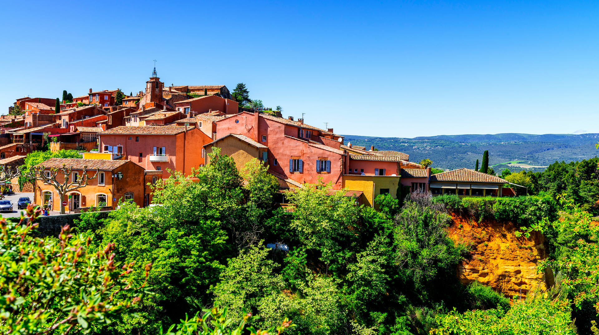 Ochre-coloured houses of Roussillon above the wooded Luberon landscape