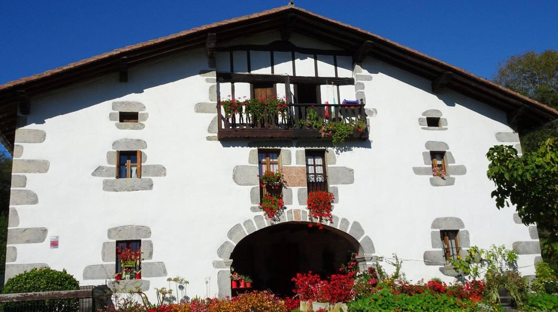 Traditional Basque farmhouse with whitewashed walls, stone detailing and flower-filled balconies