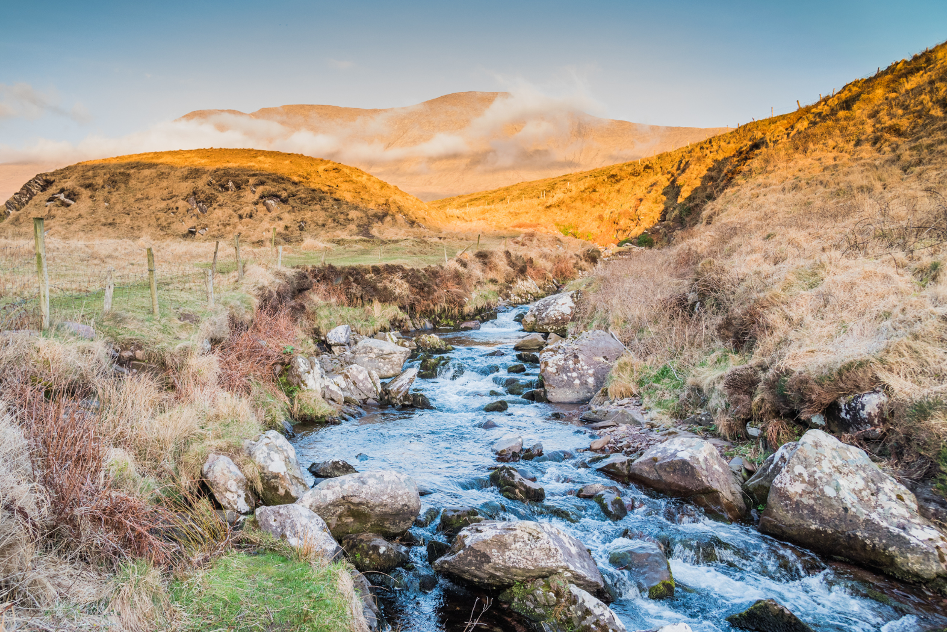 Rocky stream flowing through open grassy mountain slopes near Mount Brandon.