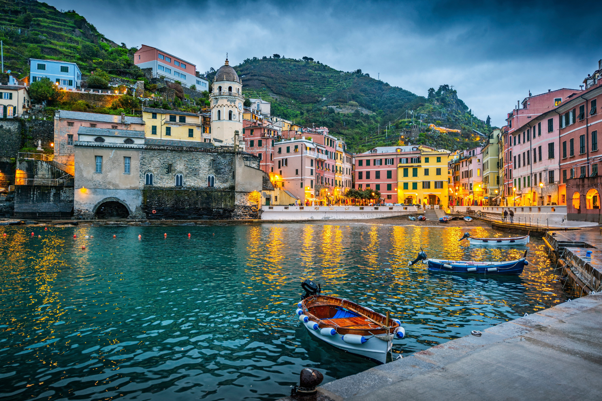Vernazza's harbour and colourful waterfront buildings illuminated at dusk.