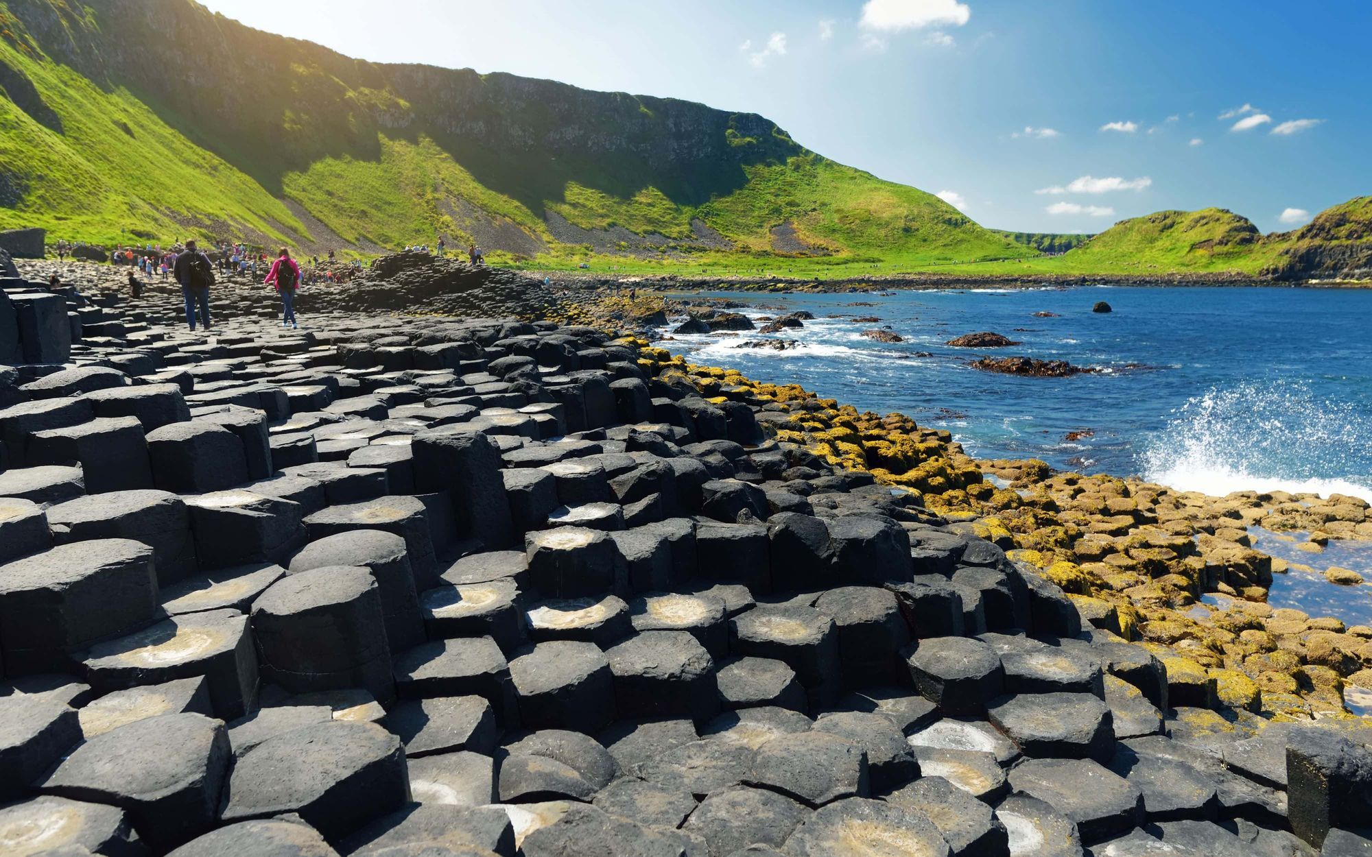 Walkers crossing basalt columns at Giant’s Causeway on Northern Ireland’s Causeway Coast Way.