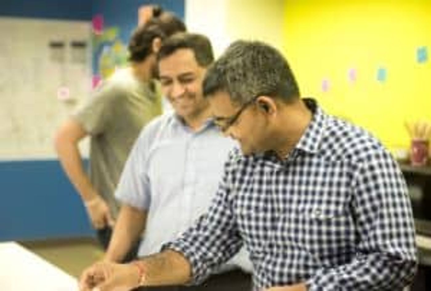Three colleagues working together at a desk in an open-plan office