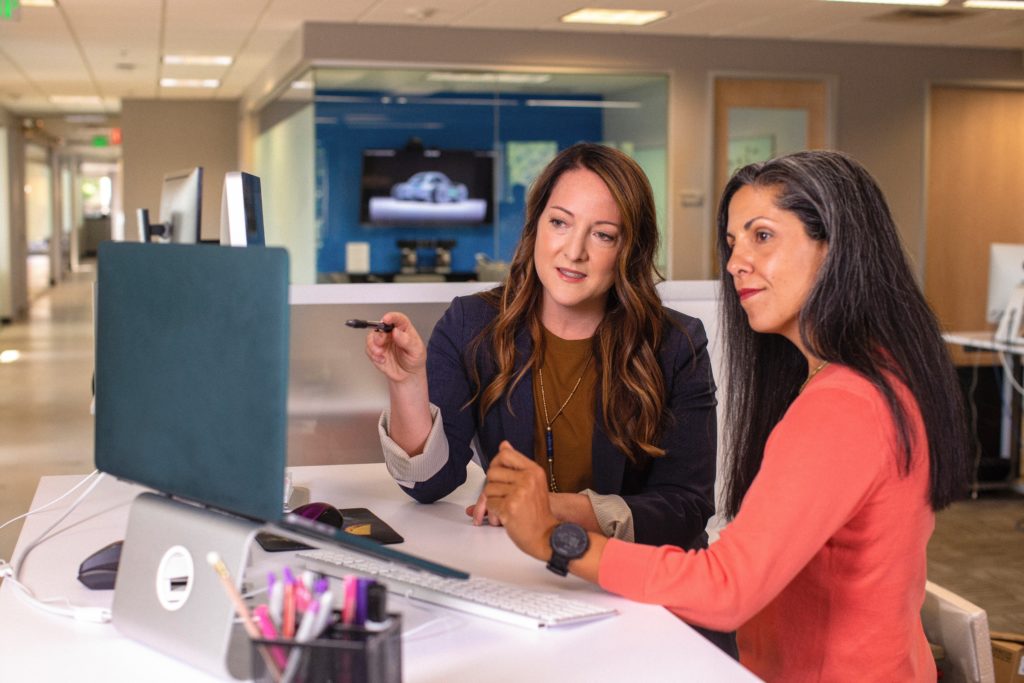 Two women working together at a desk in an open-plan office